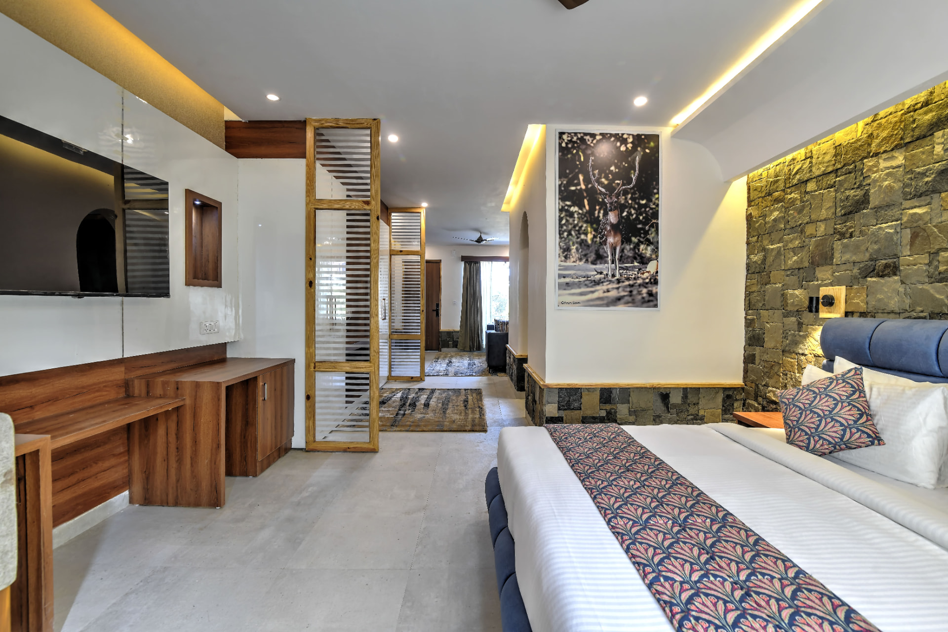 Wide view of the Sunbird Suite showing bed, work desk and stone wall in Jim Corbett