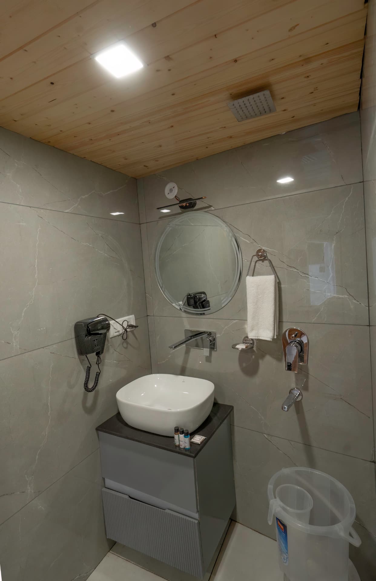 Deluxe Room modern bathroom with vessel sink, round mirror, wooden ceiling and shower