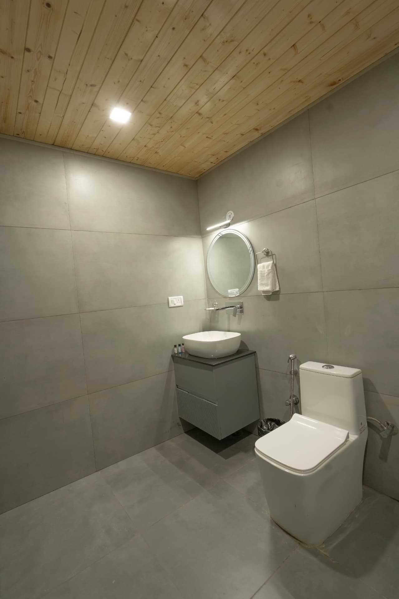 Junior Suite modern bathroom with vessel sink, round mirror and wooden ceiling at Excel Hotels Nainital