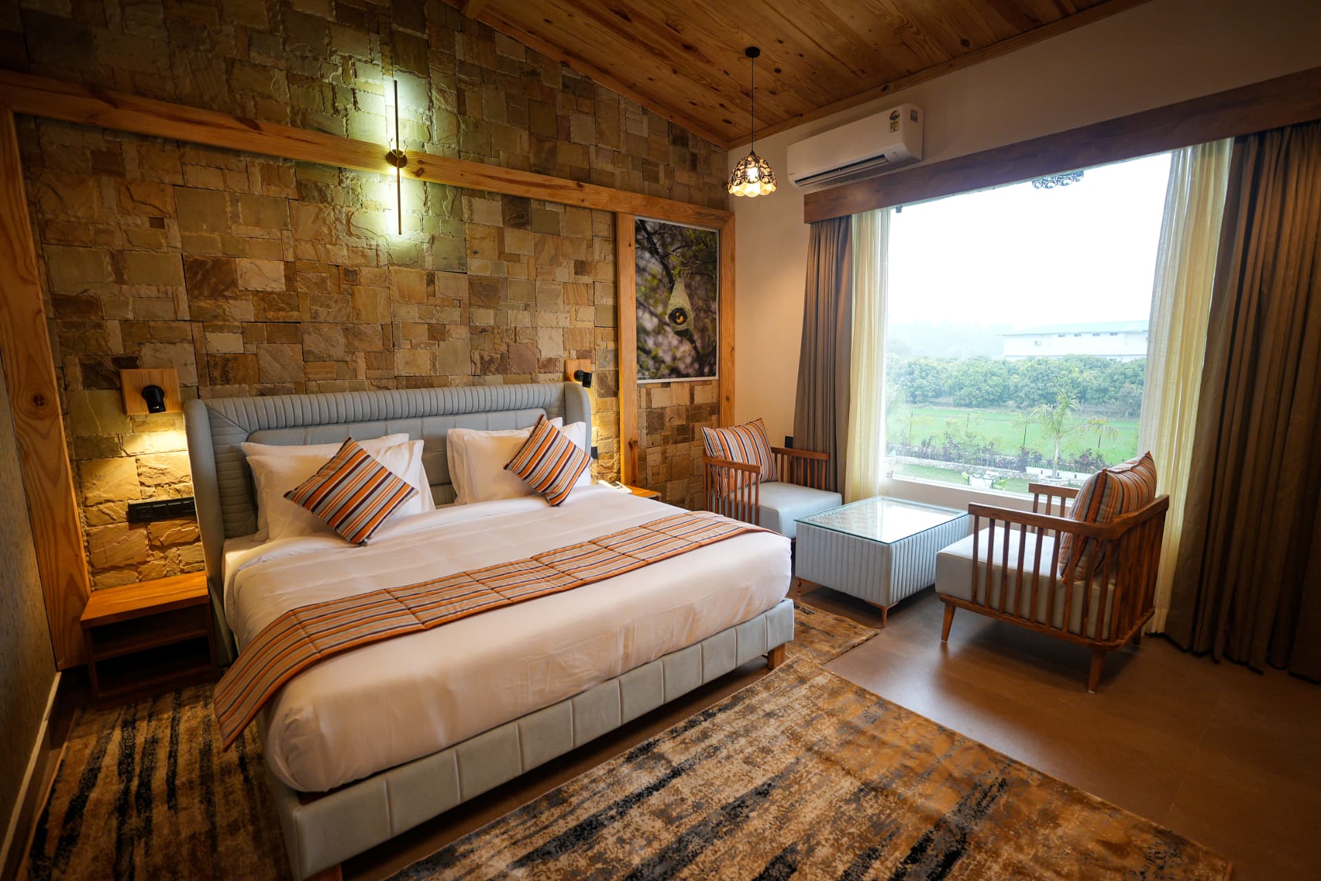 Double bed with garden view and pebble-stone accent wall in the Weaver Bird Room