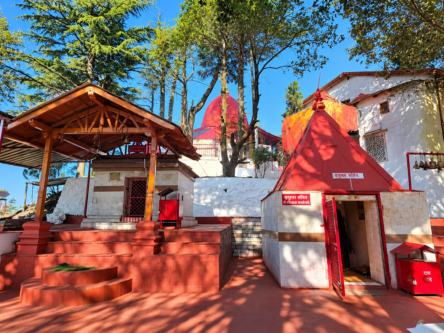 Courtyard shrines with red roofs and deodar trees at Mukteshwar Temple