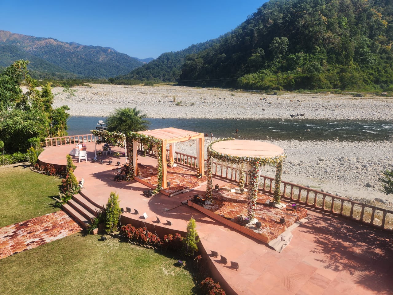 Outdoor riverside wedding venue with decorated mandap structures at Mango Bloom