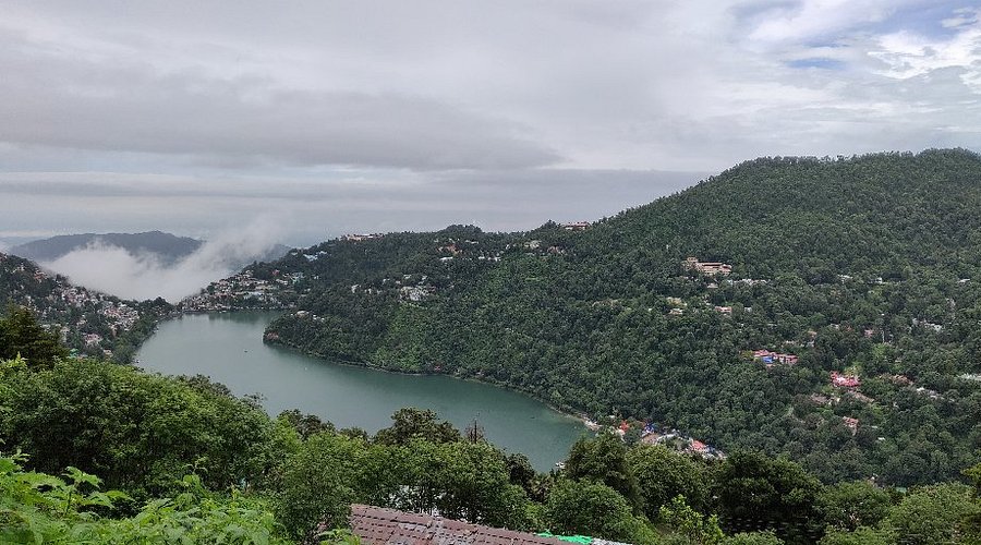 Lush green Nainital valley and Naini Lake seen from Naina Peak under a cloudy sky