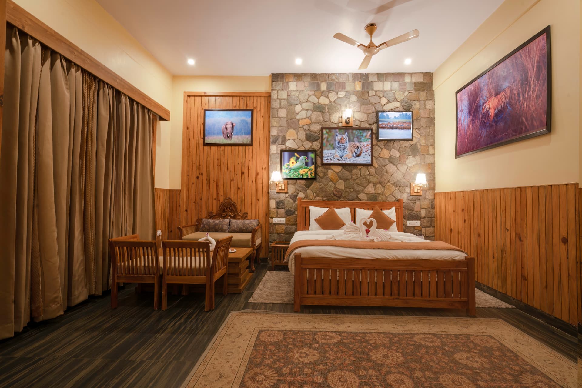 King bed, carved wooden sofa and curtained window in the Banyan Tree with Banyan View room at The Banyan Retreat Corbett