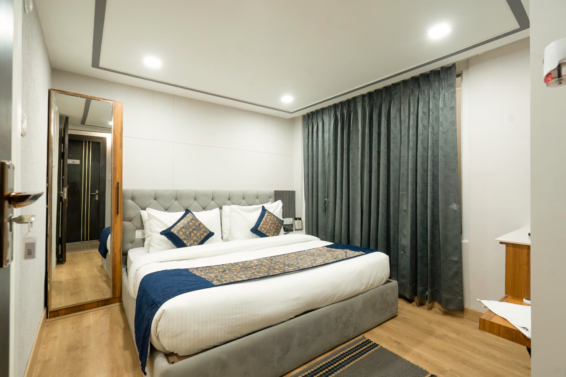 Deluxe Room comfortable king bed with blue and gold accent cushions in Nainital