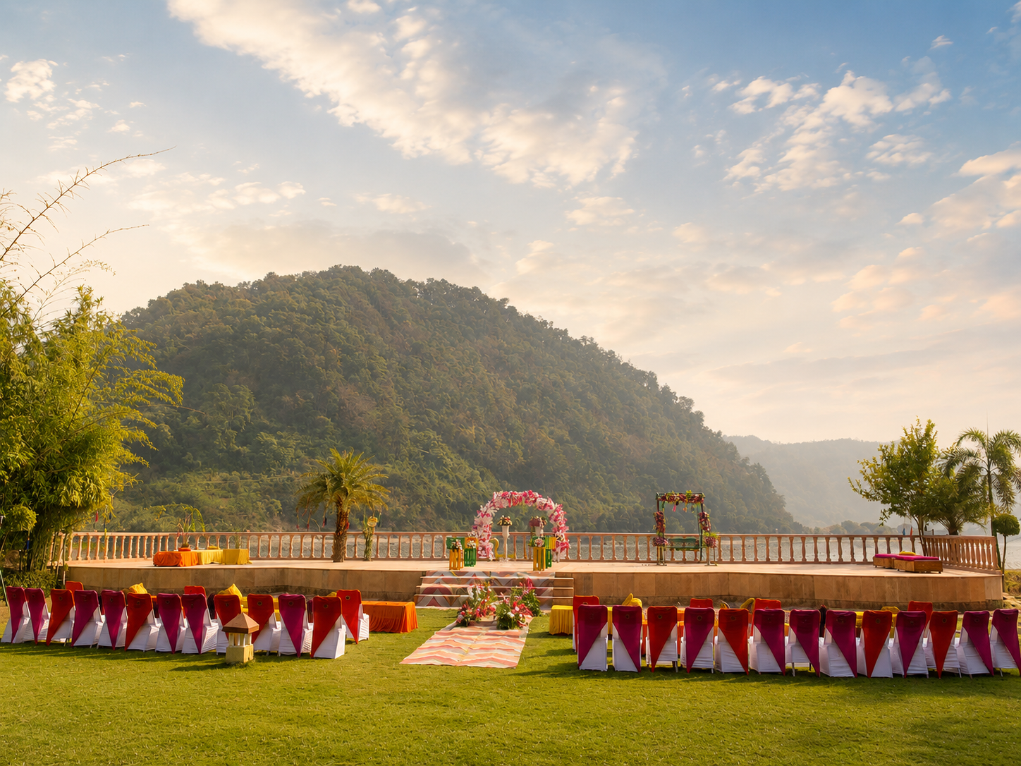Colourful outdoor wedding seating with red and pink chairs by the Kosi River at Mango Bloom River Resort