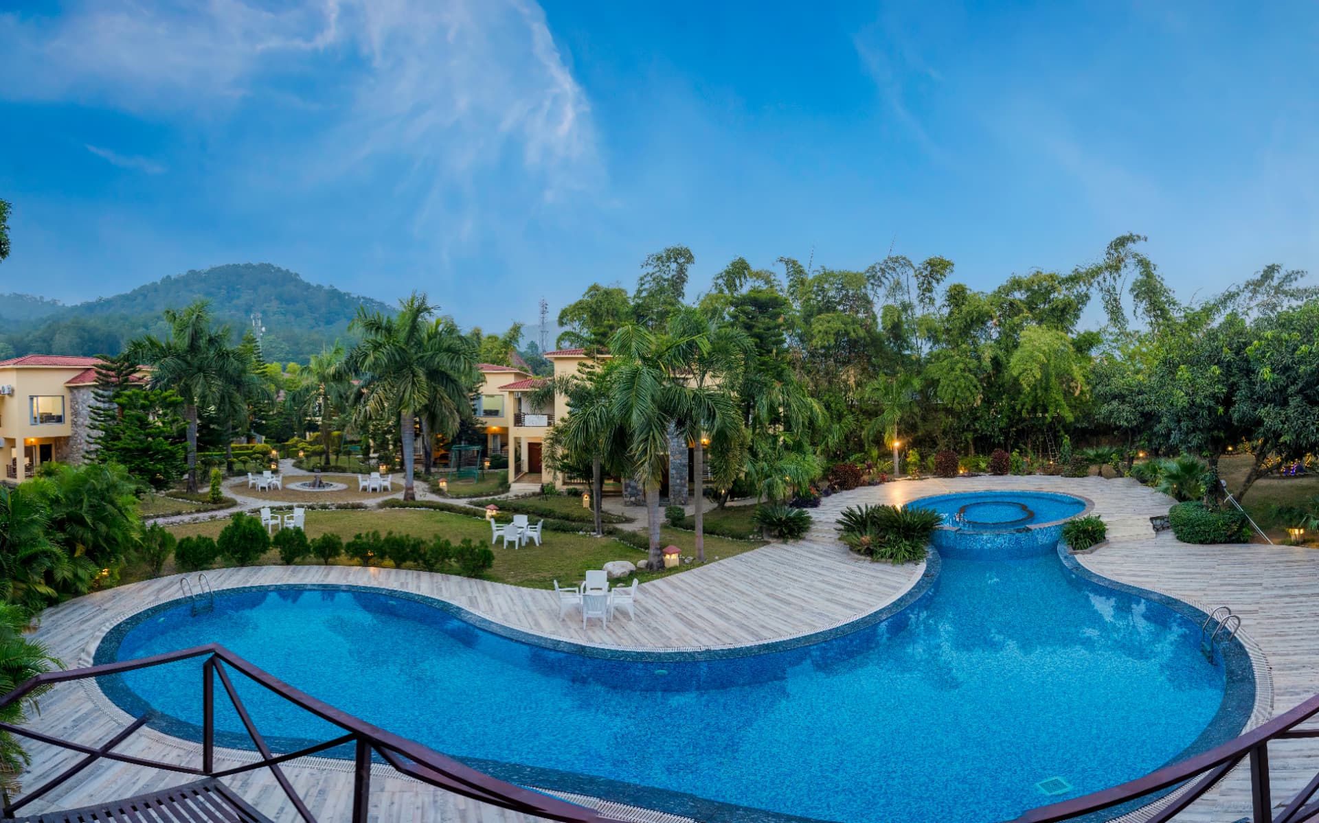 Evening view of the resort pool, villas and palm trees at Mango Bloom River Resort