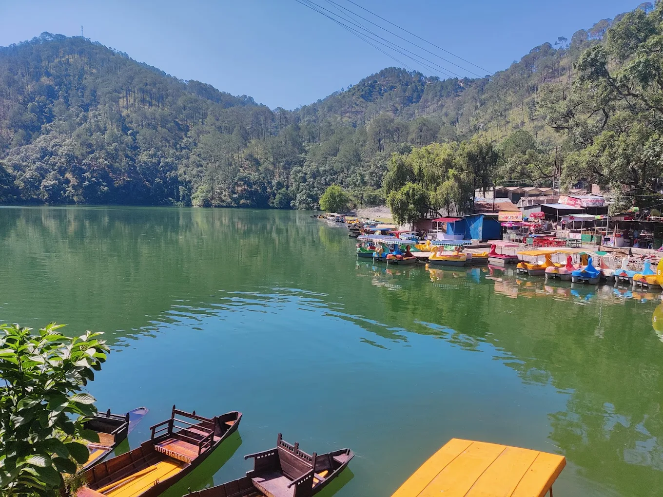 Colourful paddle boats and wooden craft lined along the shore of Sattal Lake