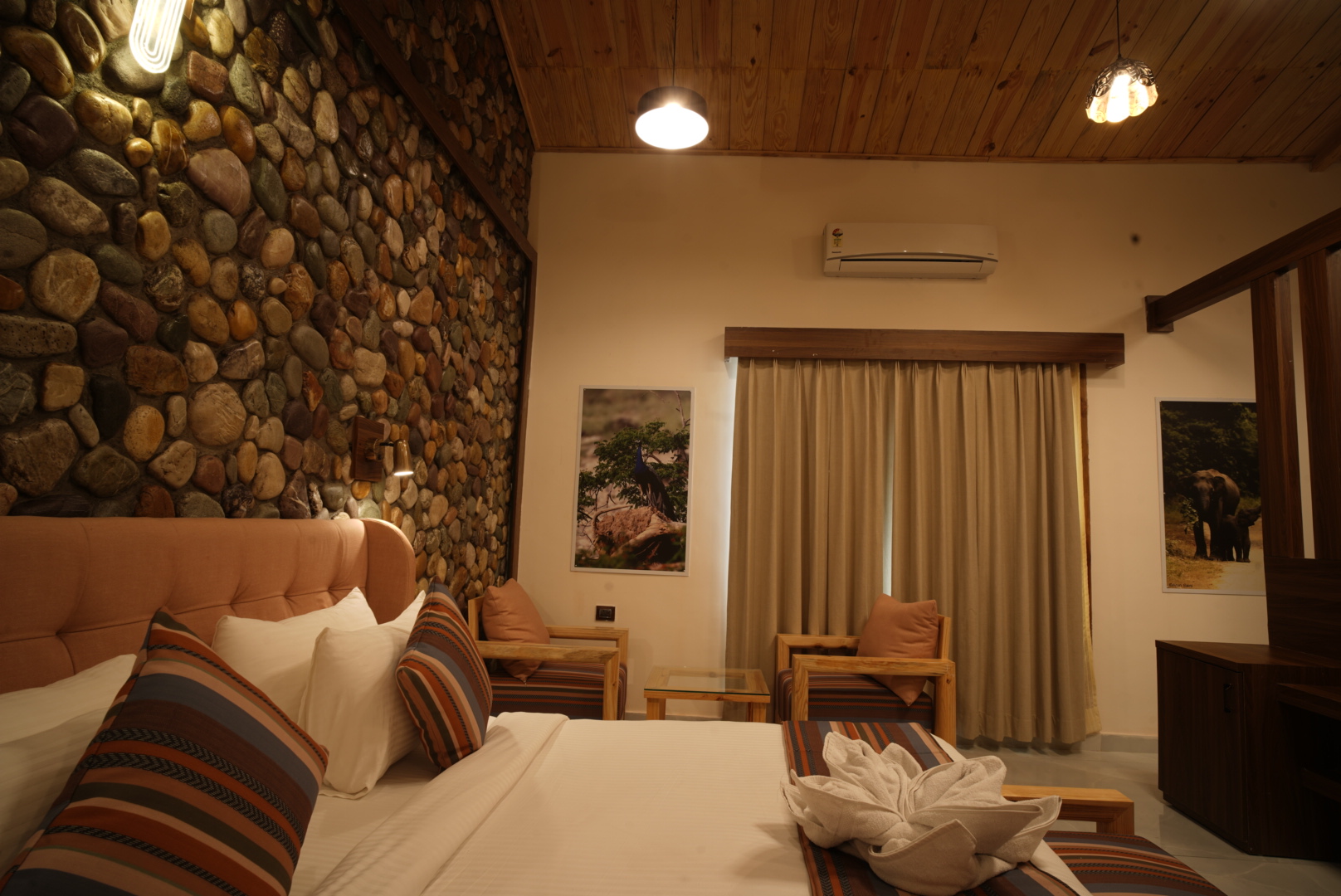 Banyan Suite at The Banyan Retreat Corbett — bedroom with river-stone feature wall, timber ceiling and seating