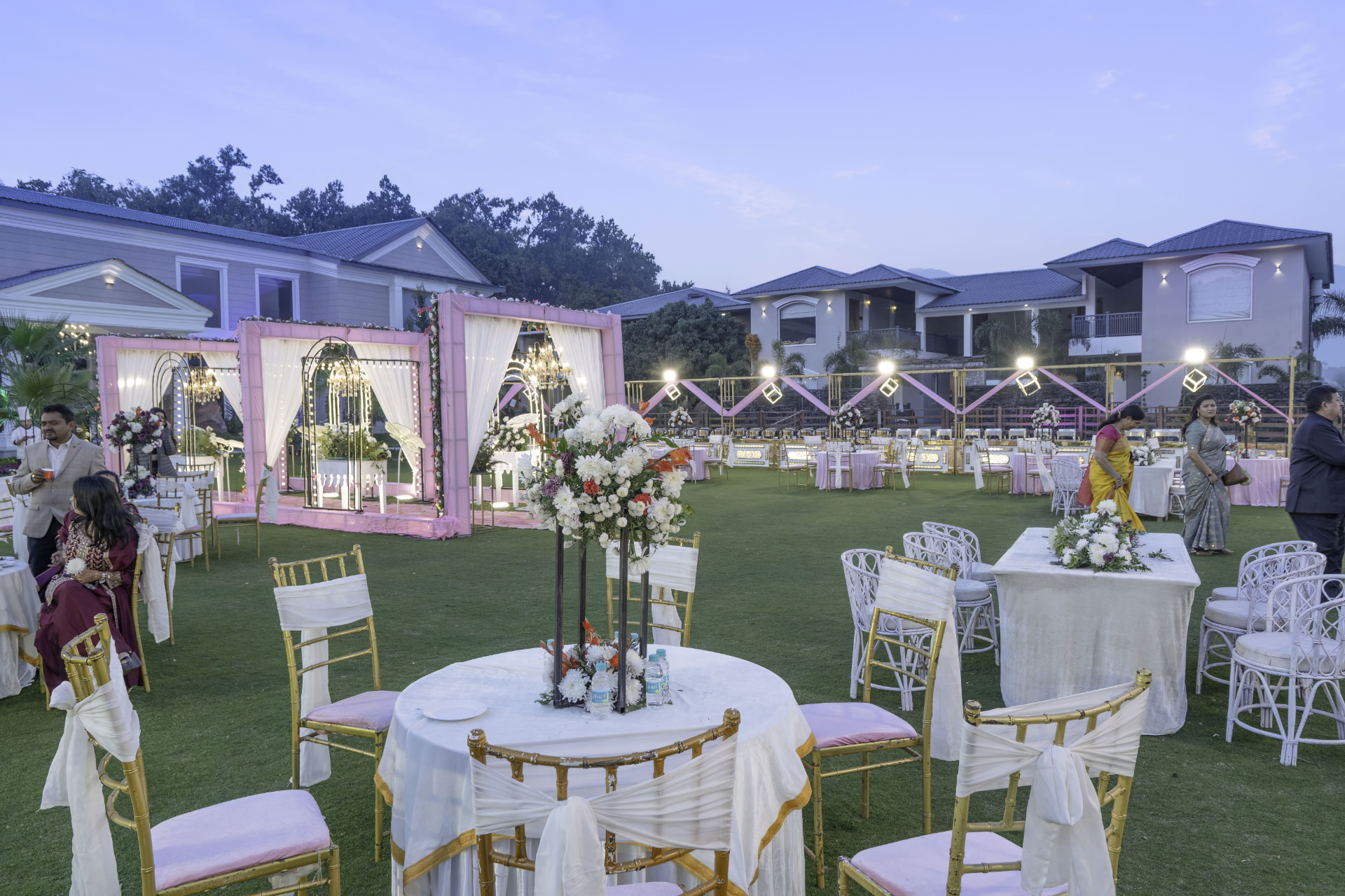 Ground-level evening view of a Kotabagh wedding lawn with decorated tables, chairs and floral mandaps