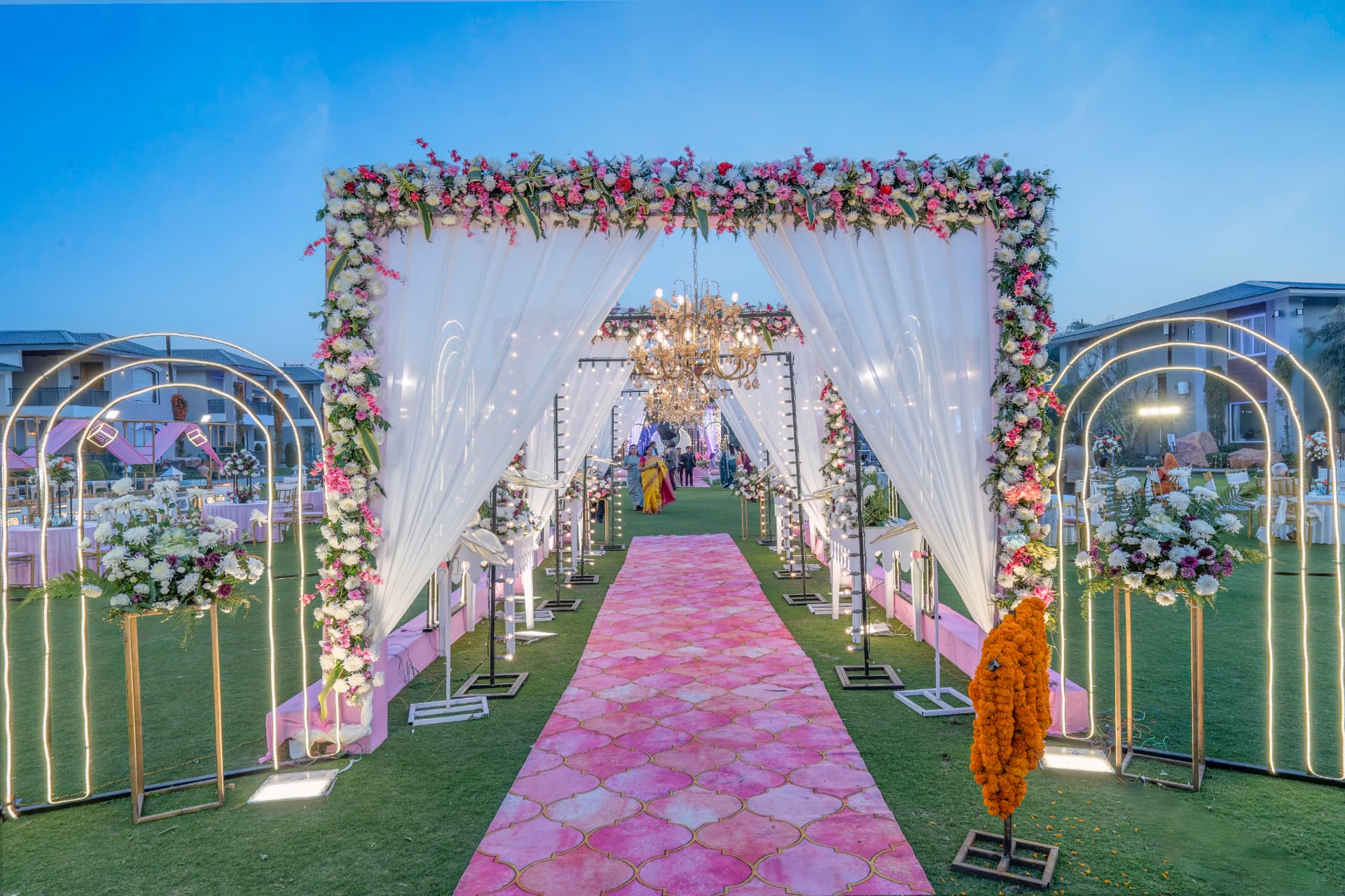 Floral mandap aisle with pink carpet, white drapes and golden arches at Excel Hotels & Resorts, Corbett