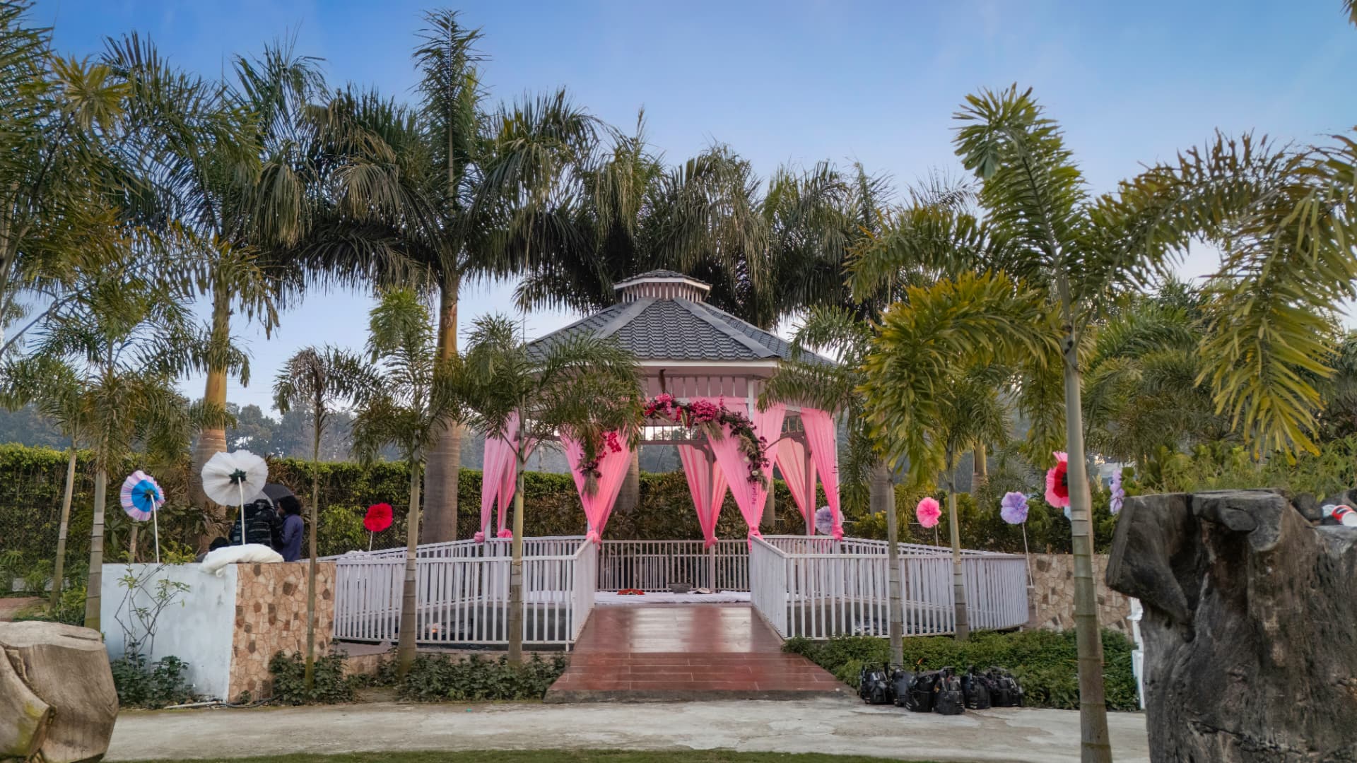 Decorated garden gazebo with pink drapes set among palm trees for a pre-wedding function