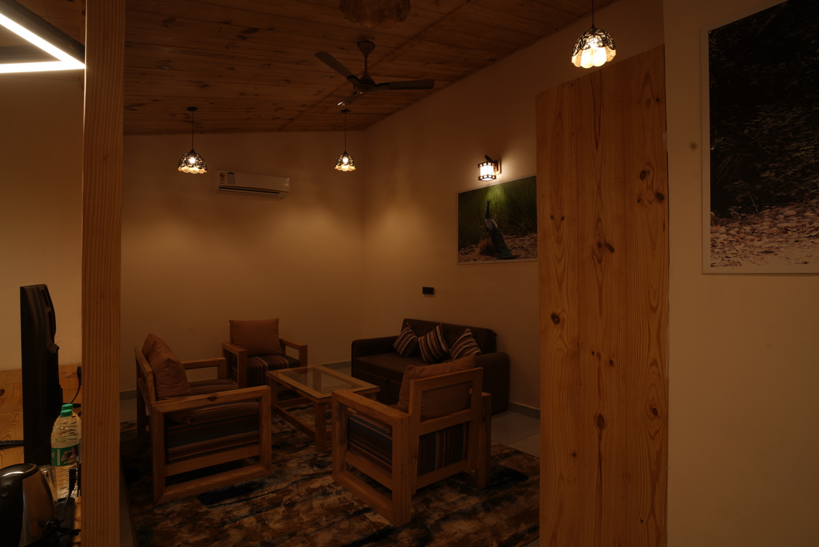 Sitting area of the Rudraksh Suite with wildlife photography and warm pendant lighting