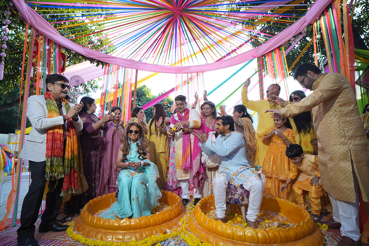 Outdoor Haldi ceremony with colourful drapes and family celebrating at La Perle River Resort