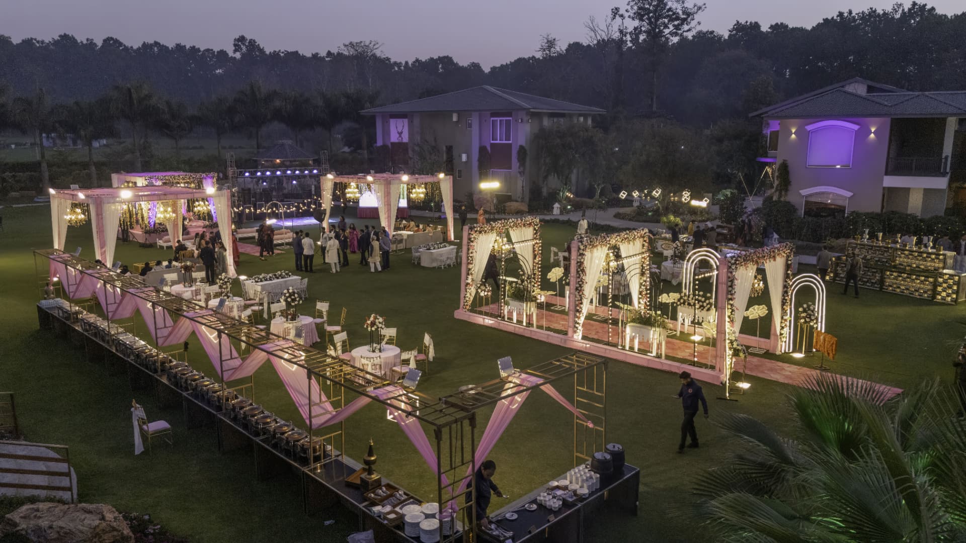 Elevated evening view of a decorated Kotabagh wedding lawn with mandaps, buffet stations and guests