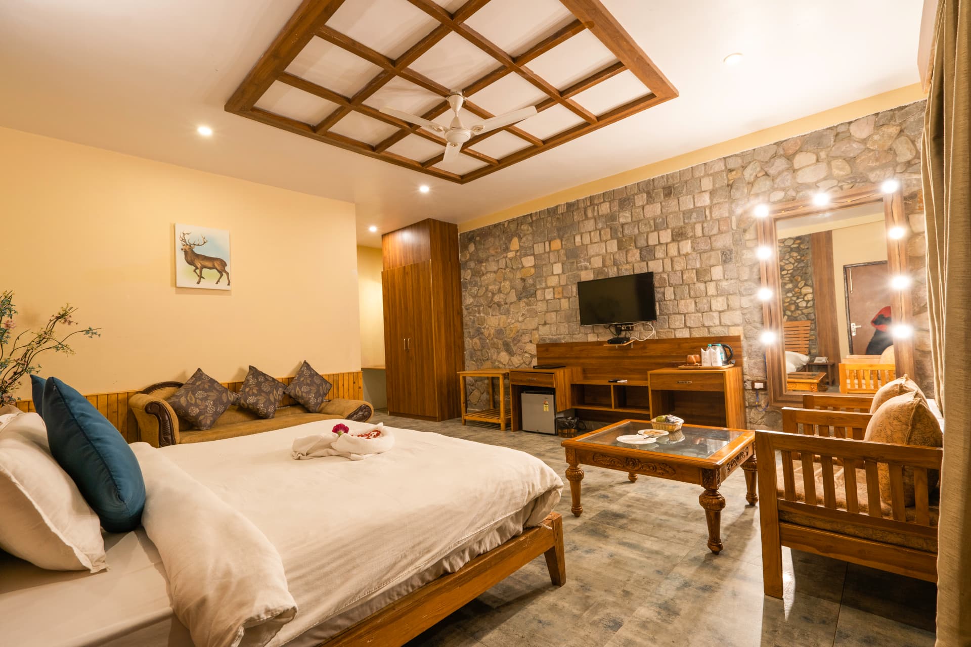 SplitsVilla room lounge seating, king bed and vanity mirror at The Banyan Retreat