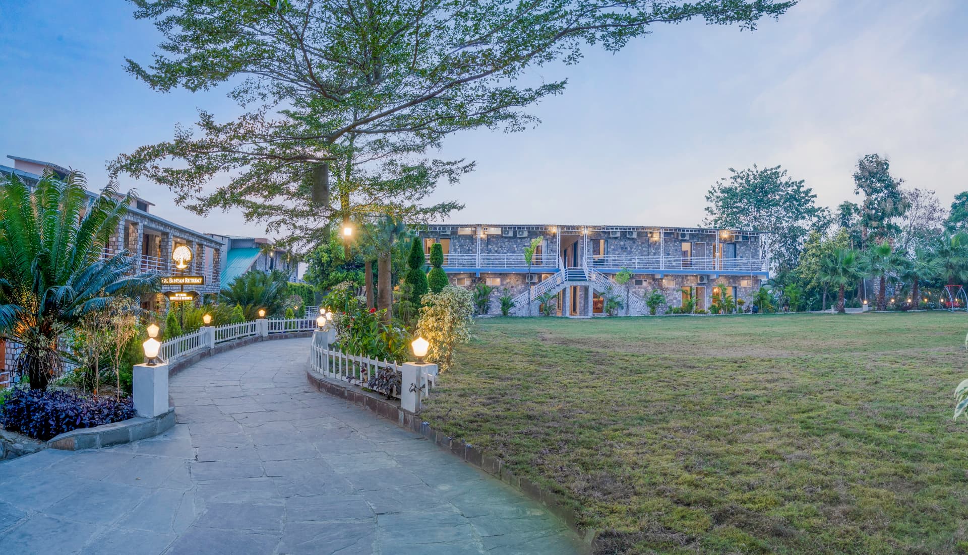 Curved garden walkway leading to the stone guest blocks and central lawn at The Banyan Retreat