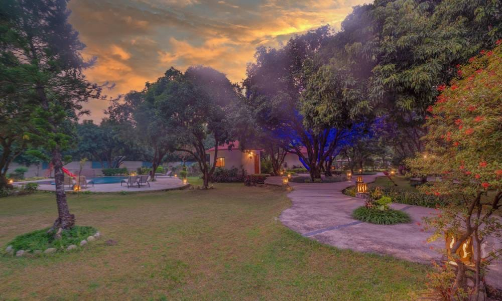 Poolside lawn with resort cottages, trees and evening lamps at La Perle River Resort