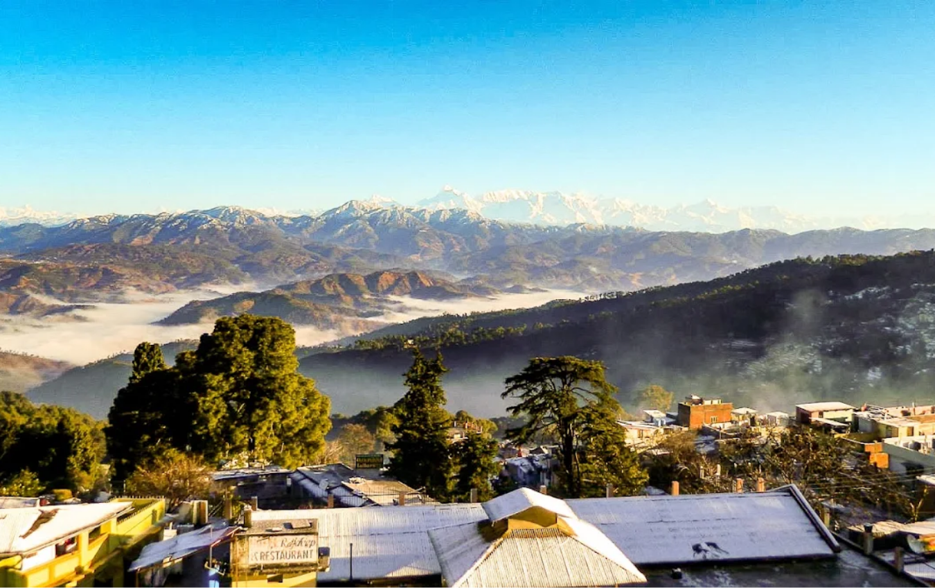 Panoramic Himalayan view with snow-capped peaks, misty valleys and Rankhet town rooftops, Uttarakhand