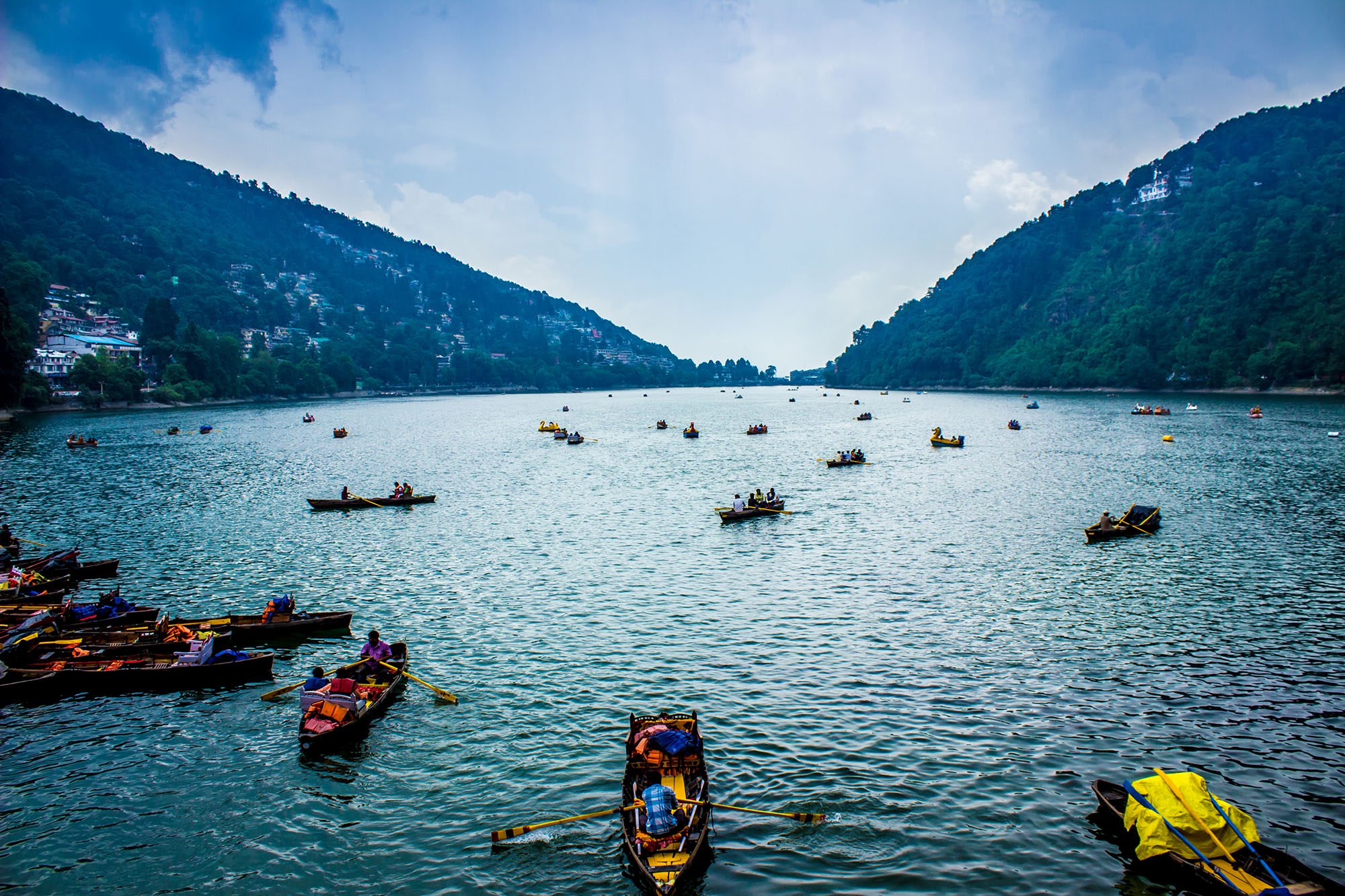 Yellow-sailed wooden boats moored along the promenade of Nainital Lake