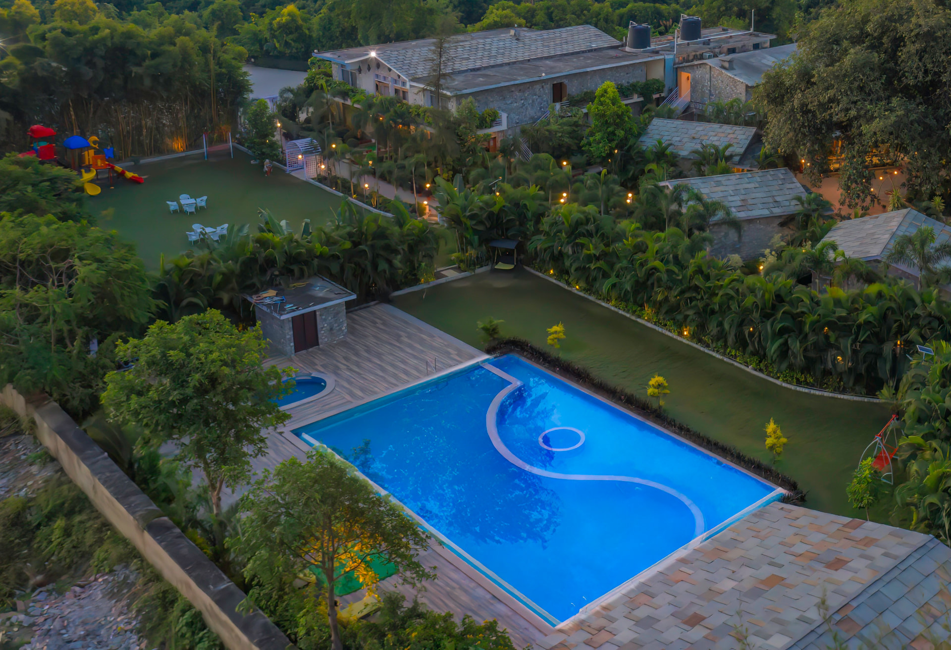 Aerial view of the swimming pool, children's play area and lawns at The Banyan Retreat, Jim Corbett