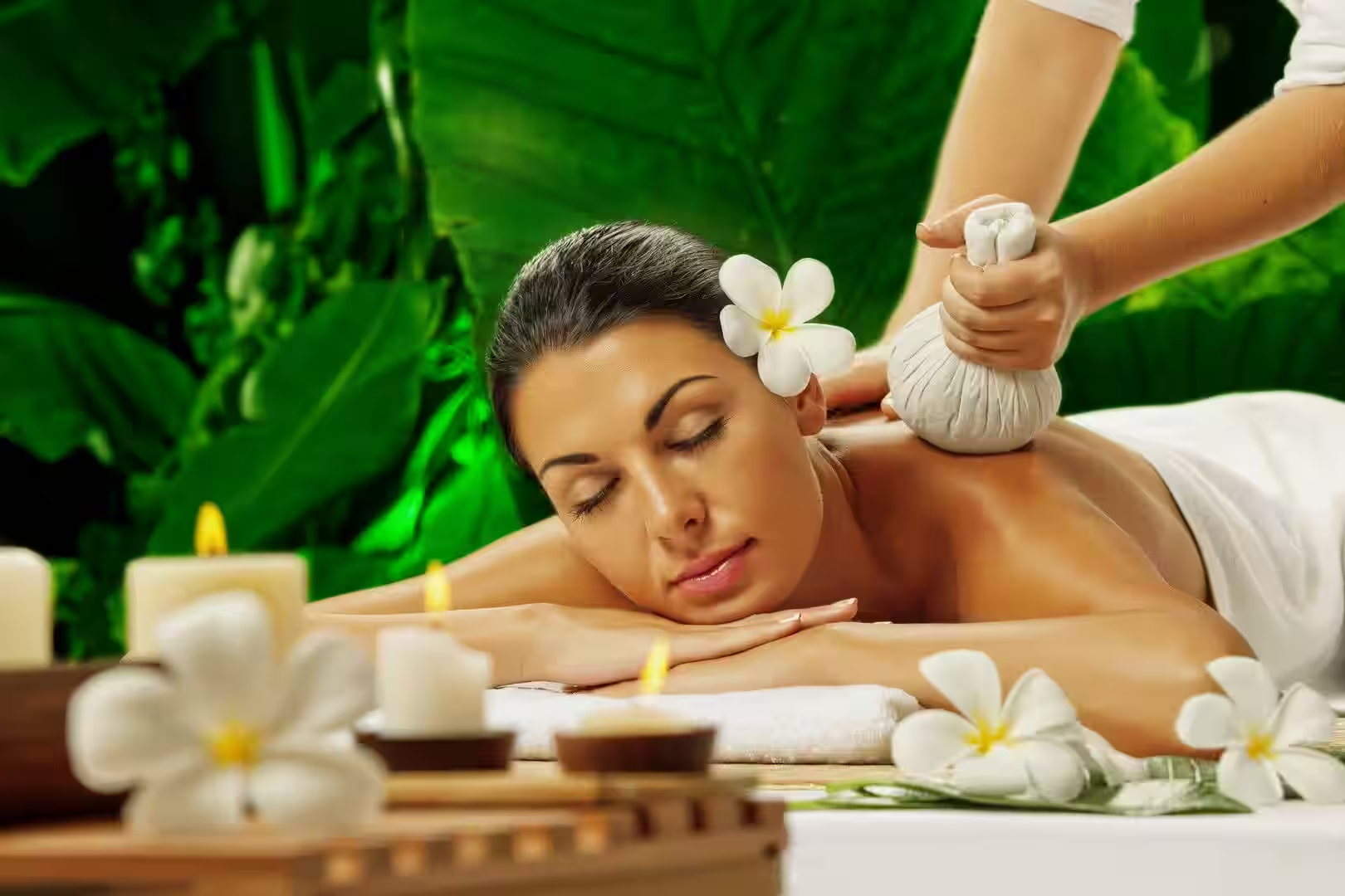 Therapist performing a herbal compress spa treatment in a tranquil wellness setting