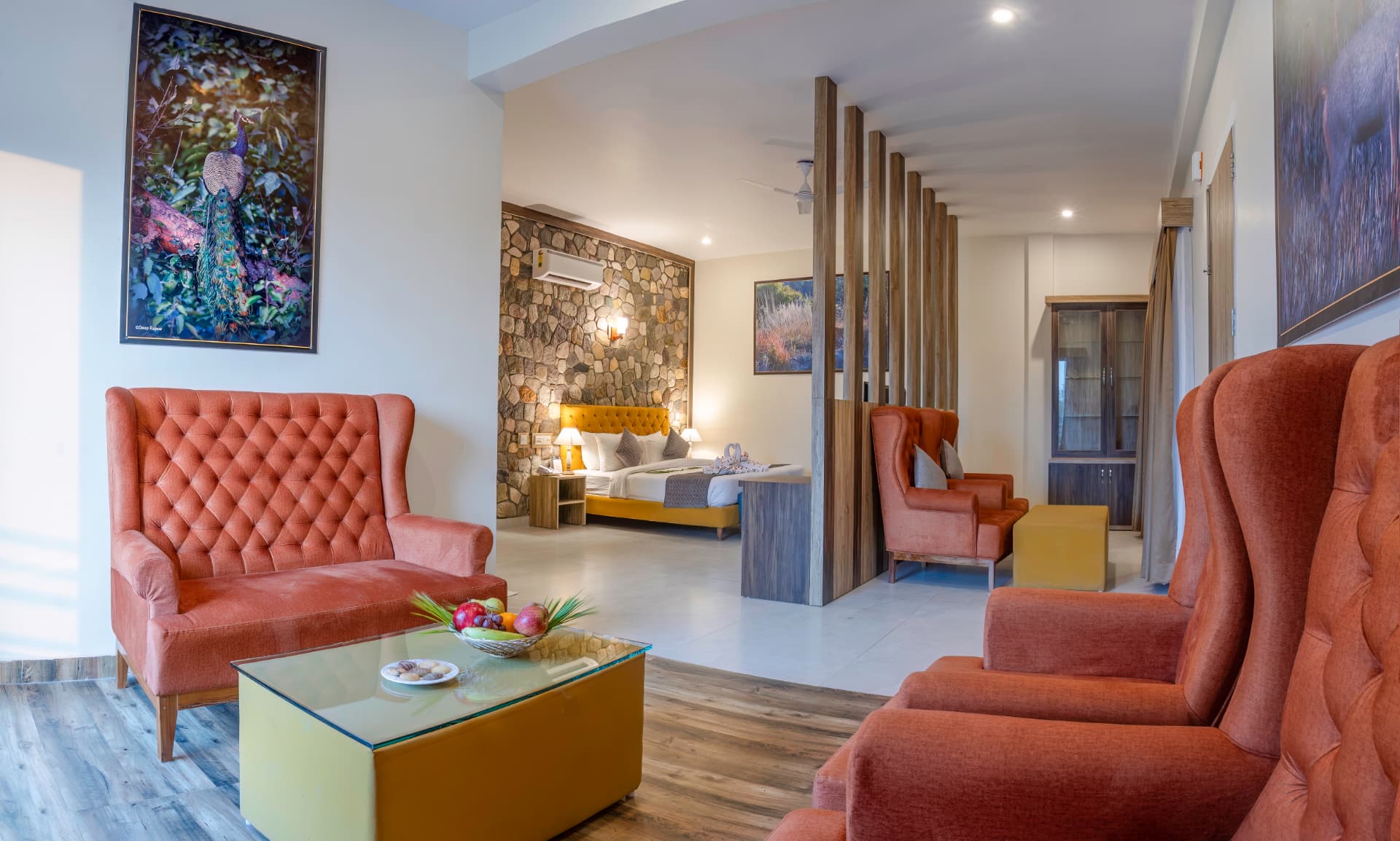 Kosi Suites lounge with upholstered chairs, peacock artwork and coffee table at The Banyan Retreat, Corbett