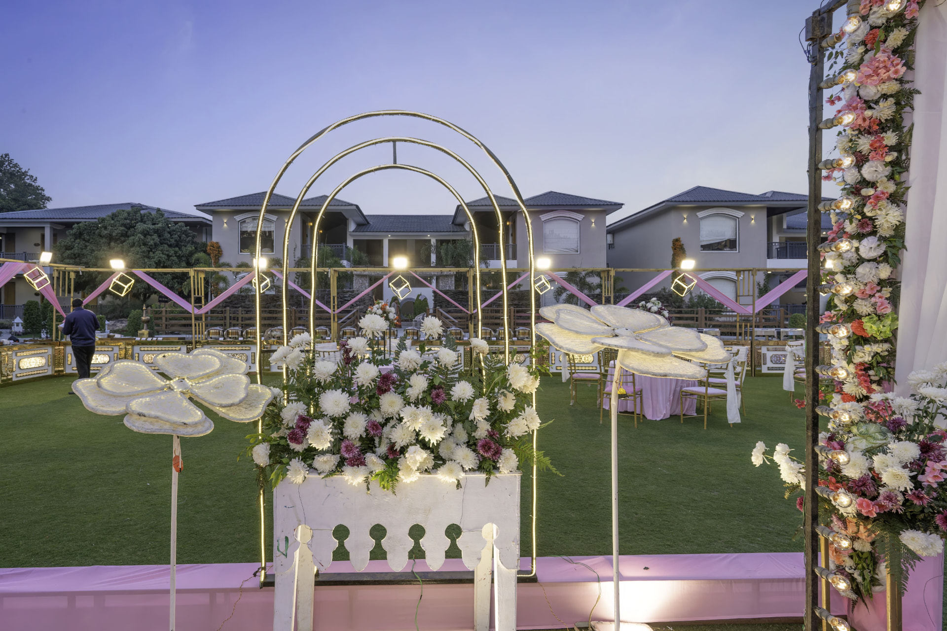 Butterfly floral decorations and glowing arches at dusk with villa buildings in the background