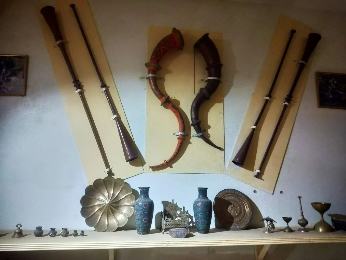 Traditional Kumaoni musical instruments, horns and brass artefacts displayed on a museum wall