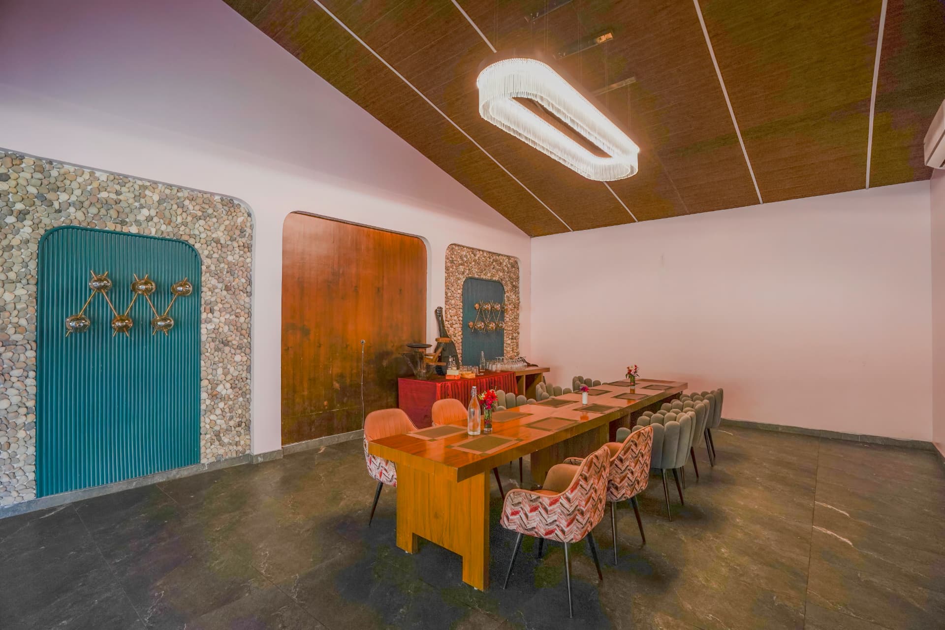 Private dining room with pebble-clad walls and a long teak table at Excel Hotels & Resorts, Corbett