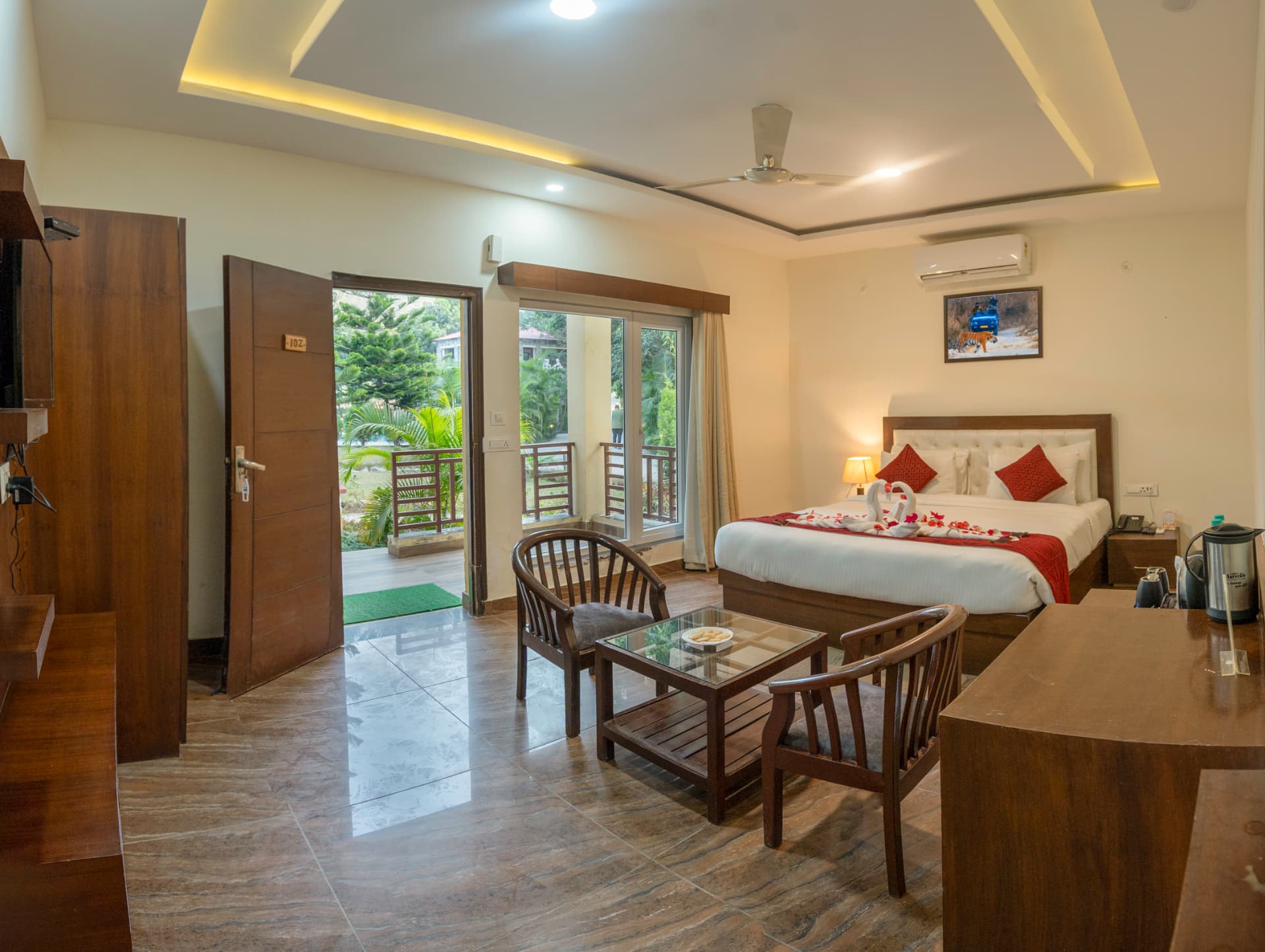 Cedar Room wide interior with double bed, TV cabinet, work desk and balcony access at Excel Hotels and Resorts Corbett