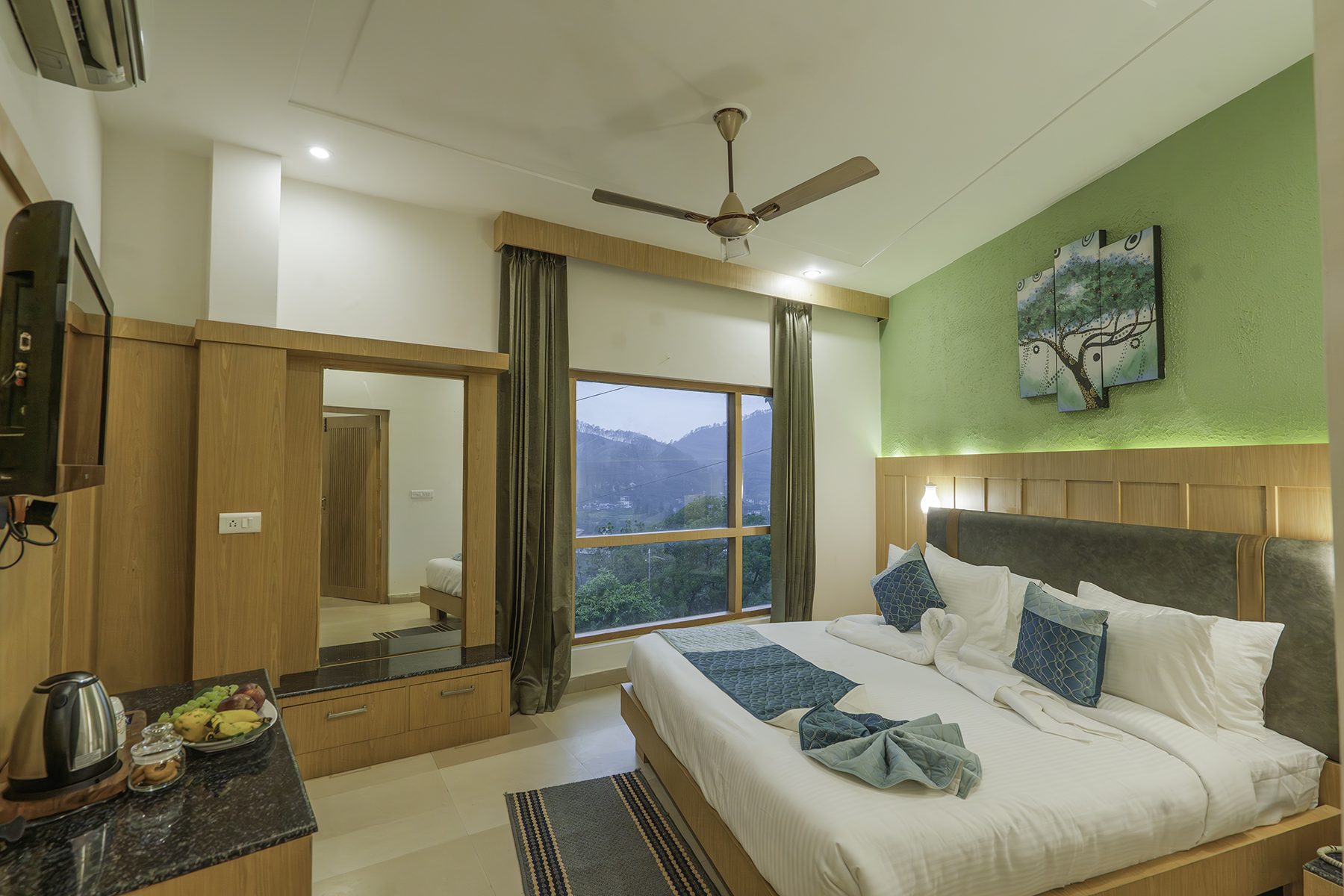 Premium Room with king bed, green feature wall and mountain-facing window at Excel Hotels Bhimtal