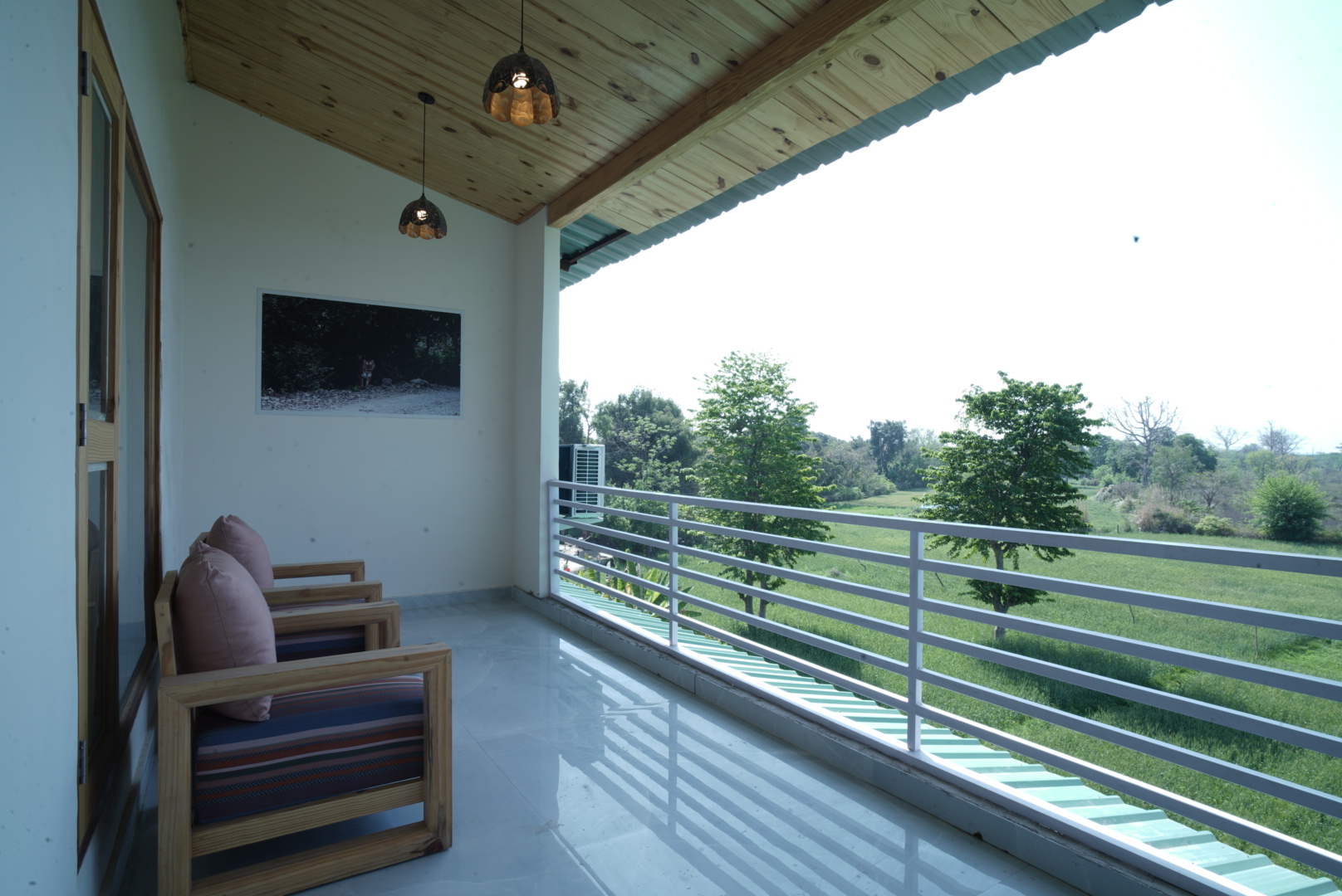 Banyan Suite at The Banyan Retreat Corbett — private balcony with seating overlooking green fields and trees