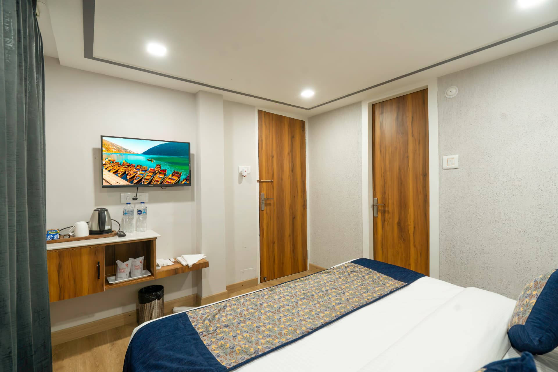 Deluxe Room interior with king bed, wall-mounted TV and wooden wardrobe in Nainital