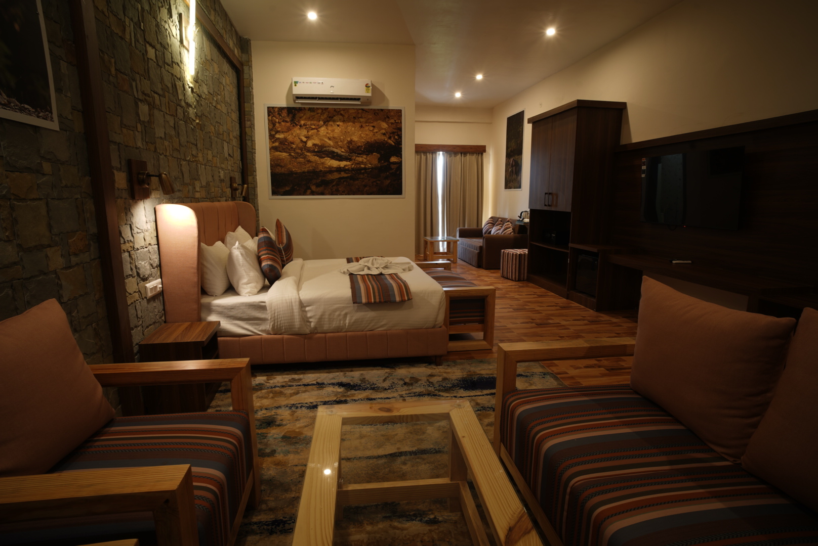 Wide view of the Ficus Suite with bed, lounge seating and television unit