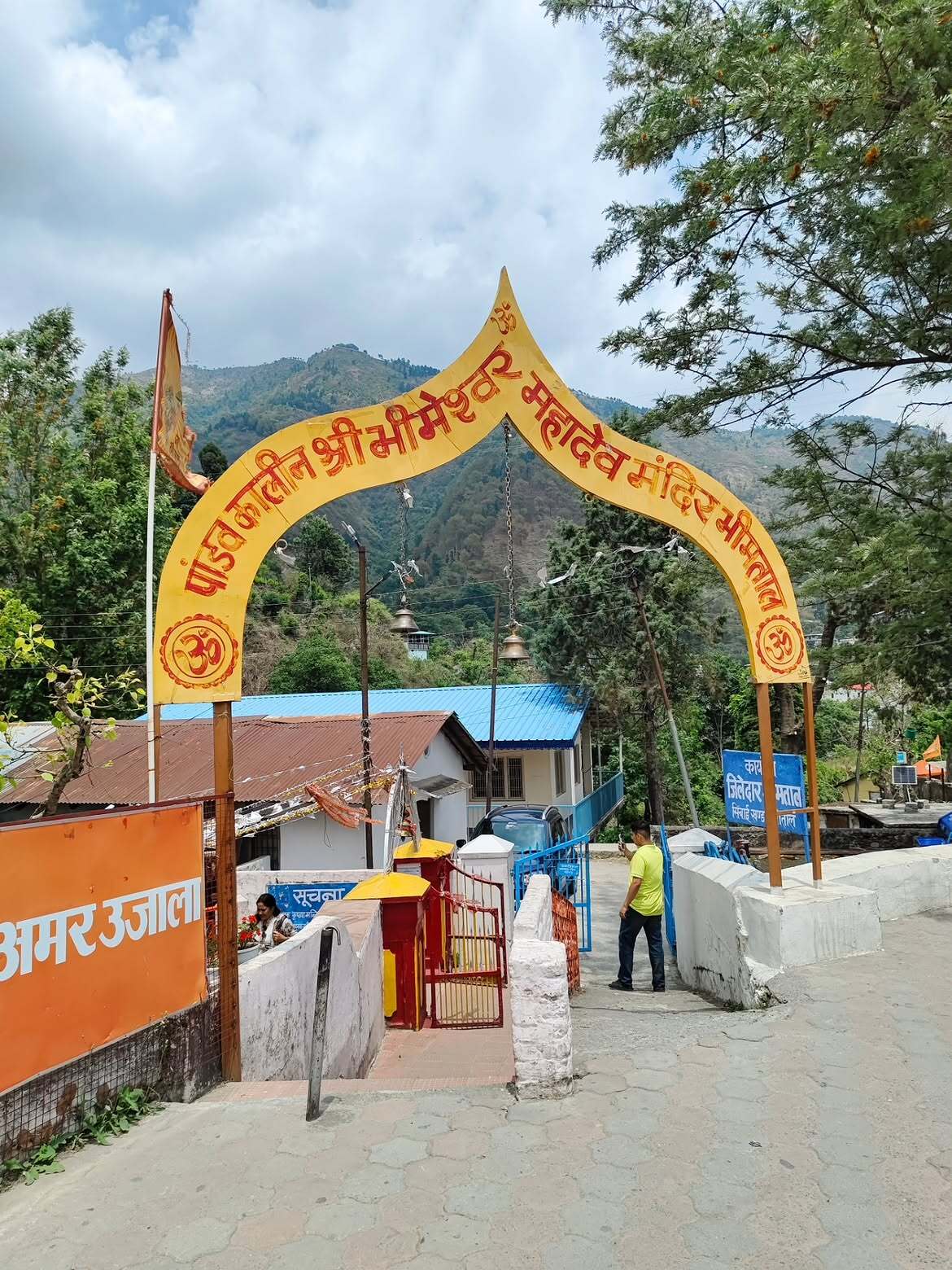 Bright yellow entrance arch of Bhimeshwar Mahadev Temple set against the green hills of Bhimtal