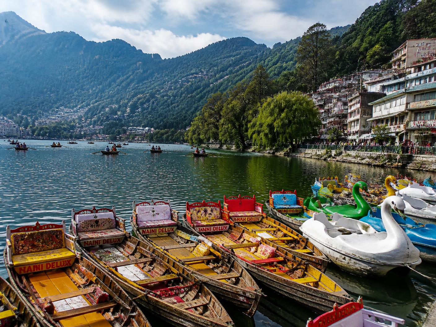 Colourful boats on Naini Lake with the forested hills of Nainital behind